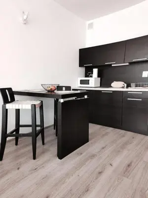 a kitchen with black cabinets and a table and a chair at Boho Studio 4 pools 10min to the beach in Burgas City