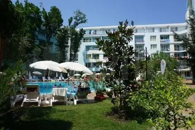 a pool with chairs and umbrellas next to a building at Yassen Sunny Beach in Sunny Beach