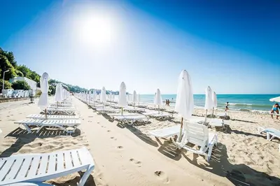 a row of lounge chairs and umbrellas on a beach at Cozy Apartment in Grand Fort Noks with Sea View in Sveti Vlas