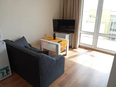 a living room with a couch and a television at Cozy Apartment in Grand Fort Noks with Sea View in Sveti Vlas