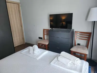 a bedroom with a bed and a tv and two chairs at Апартамент на център Приморско in Primorsko