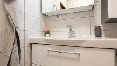 a white bathroom with a sink and a mirror at Апартамент Уютна почивка in Burgas City