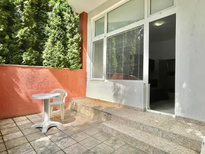 a table and a chair sitting outside of a window at Green Fort Noks - Private apartment - BSR - 3 in Sunny Beach
