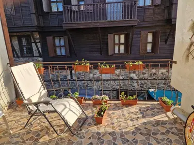 a chair sitting on a patio with potted plants at Apartament Magi in Sozopol