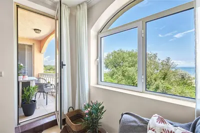 an arched window in a living room with a view of the ocean at Beach Front Luxury Apartment in Sozopol