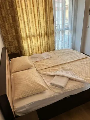 a bed with two pillows on it in front of a window at Апартамент в Риф 2 in Burgas City