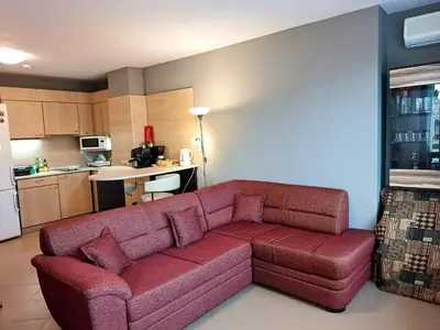 a living room with a red couch in a kitchen at Hills view apartment in Sunny Beach