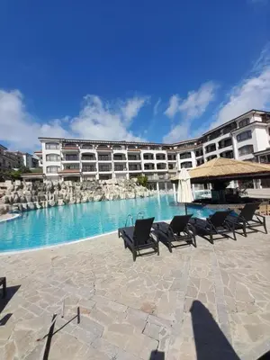 a large building with chairs and a swimming pool at Nice 2 Bedroom Apartment with Sea and Poolview near Aheloy in Kableshkovo