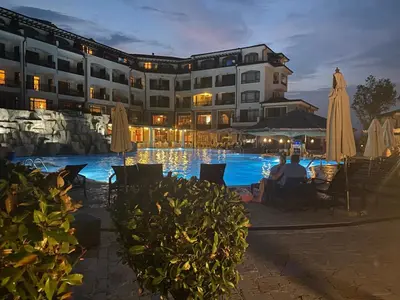 a man sitting next to a pool at a hotel at The Vineyard Spa&Resort Apartment with private garden near Aheloy in Kableshkovo