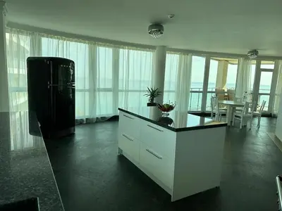 a living room with a refrigerator and a table at Beach Front Luxurious Two Bedroom Apartment in Byala