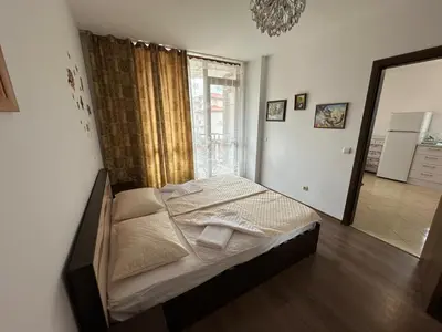 a bedroom with a bed and a large window at Апартамент Emilia in Ravda