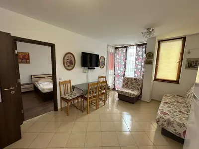 a living room with a table and a bedroom at Апартамент Emilia in Ravda