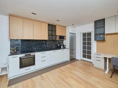 a large kitchen with white cabinets and a table at n17 Garden - Parking - WorkDesk - Blackout Rolls- Netflix - Wash&Dry in Burgas City