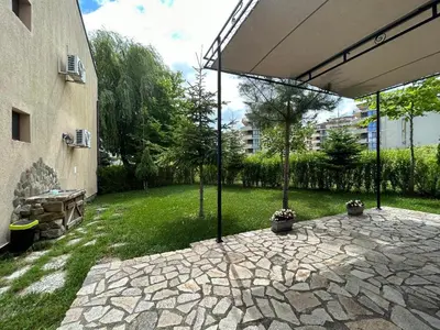 a patio with an umbrella next to a building at Вилно селище Зора in Shkorpilovtsi
