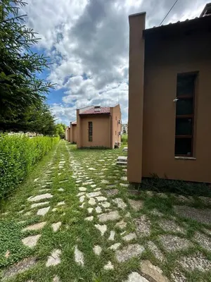 a cobblestone road next to a house and a building at Вилно селище Зора in Shkorpilovtsi