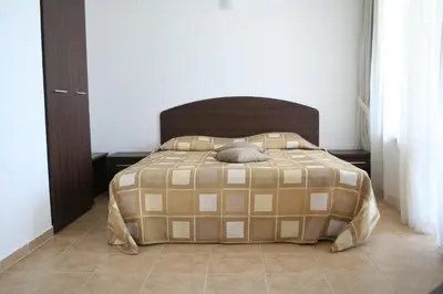 a bed with a brown and tan comforter in a bedroom at Apartments Helios in Pomorie