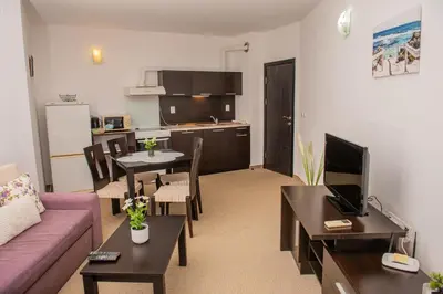 a living room with a couch and a table and a kitchen at Atlantis Resort Private 1BD apart by Flat Mаnager in Burgas City