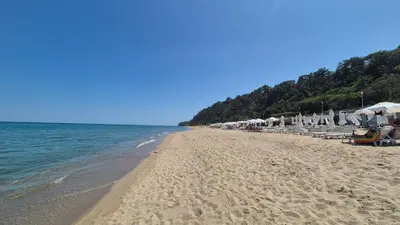 a beach with umbrellas and chairs and the ocean at Amazing panorama sea view apartment in Byala