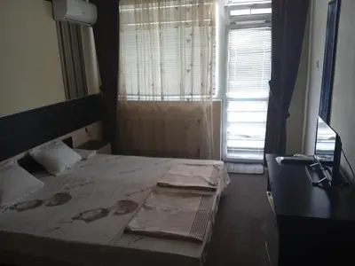a bedroom with a bed and a window with curtains at Къща за гости дани in Primorsko