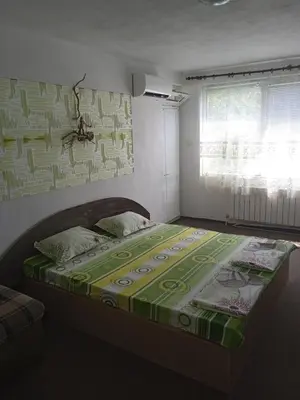 a bedroom with a bed with a green and white comforter at Къща за гости дани in Primorsko