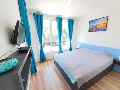 a bedroom with blue curtains and a bed and a tv at Neptun-Blue in Primorsko