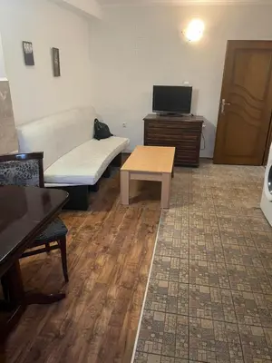 a room with a couch and a table and a tv at Хотел Стоянови in Ravda