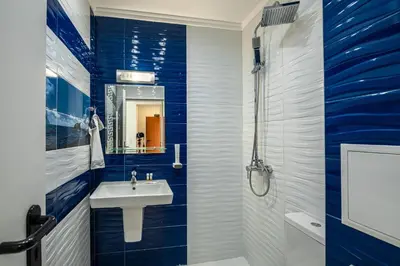a blue and white bathroom with a sink and a shower at Апартаменти с чадъри и шезлонги на плажа - Свети Никола Каваците in Sozopol