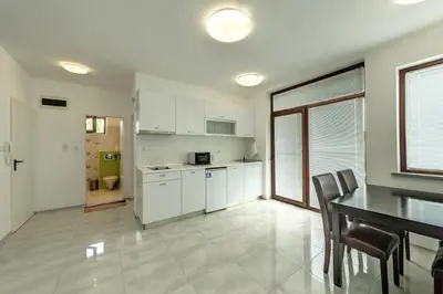 a kitchen with white cabinets and a table and chairs at Апартаменти с чадъри и шезлонги на плажа - Свети Никола Каваците in Sozopol