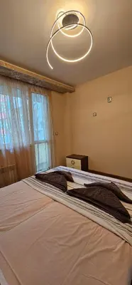 a bedroom with a large bed and a chandelier at Rada's Apartment BSV in Burgas City