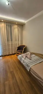 a bedroom with a bed and a chair on a wooden floor at Rada's Apartment BSV in Burgas City