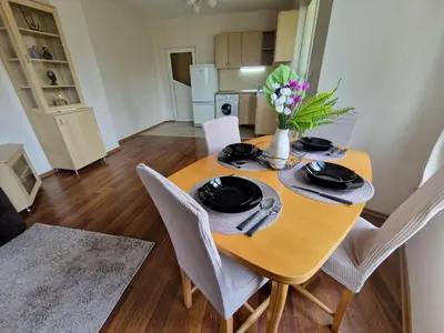 a dining room table with chairs and a vase of flowers on it at Lazur Sea Garden 2 in Burgas City