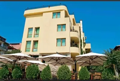 a tall building with umbrellas in front of it at Къща за гости Беглик таш 3 in Primorsko