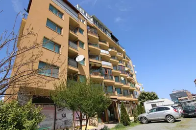 a tall building with cars parked in front of it at Amadeus 5 - Menada Apartments in Sunny Beach