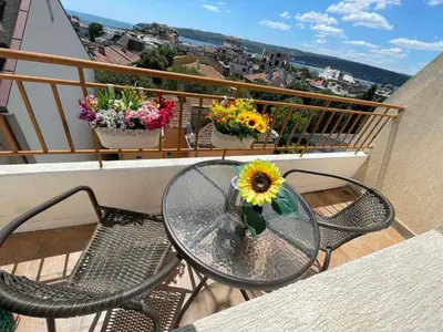 a table and chairs on a balcony with flowers at Roman Thermae, steps from the sea with free parking in Varna City