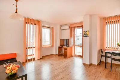 a living room with wooden floors and windows at Roman Thermae, steps from the sea with free parking in Varna City