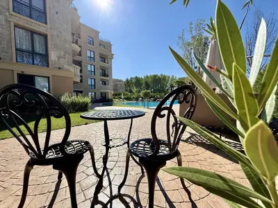 a patio with two chairs and a table and a plant at Menada Aphrodite Green Apartments in Sunny Beach