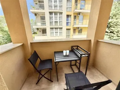 a balcony with a table and chairs and a building at Menada Aphrodite Green Apartments in Sunny Beach