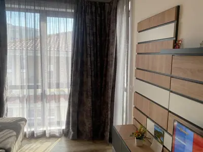 a bedroom with a large window with curtains at Sea Sunrise Apartment in Burgas City