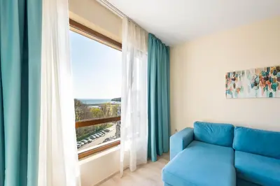 a living room with a blue couch and a large window at Blue Horizon Suite in Varna City