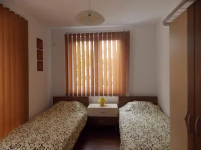 a bedroom with two beds and a table and a window at Guest House Nedelchevi in Primorsko