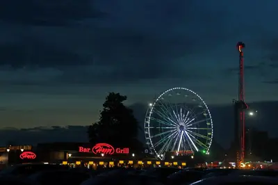 a ferris wheel at night with neon signs at Sea Garden Marina 1 Apartment Varna in Varna City