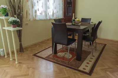 a dining room table with black chairs on a rug at Sea Garden Plaza Apartment - Free Parking in Burgas City