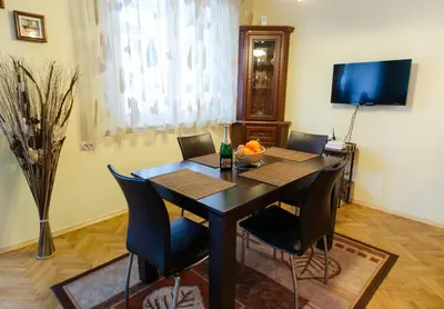 a dining room with a table with chairs and a television at Sea Garden Plaza Apartment - Free Parking in Burgas City