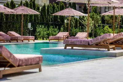 a pool with lounge chairs and umbrellas at J'ADORE Secret Garden A&K Deluxe Studio in Sunny Beach
