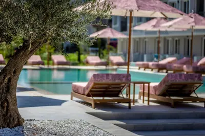 a pool with lounge chairs and a table with umbrellas at J'ADORE Secret Garden A&K Deluxe Studio in Sunny Beach