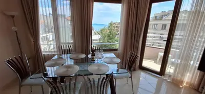 a dining room with a table and chairs and a large window at Сарафово холидейс in Burgas City
