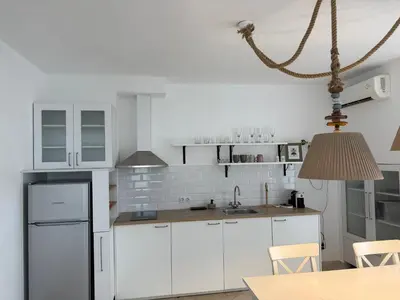 a kitchen with white cabinets and a table and a lamp at Flores Garden Pool Side and Sea View Apartment in Chernomorets