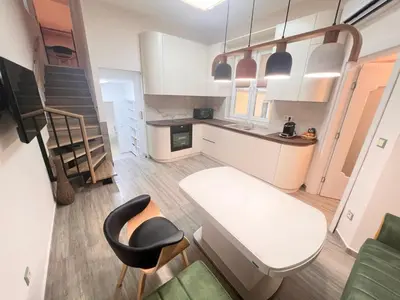 a small kitchen with a white table and a chair at New Yorker 2 bedroom apartment in Varna City