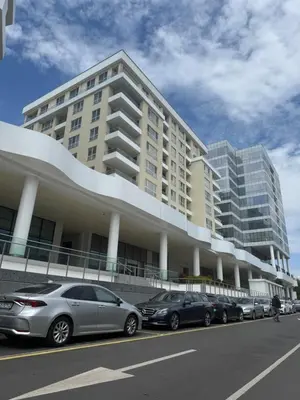 a large building with cars parked in front of it at Central Park 7 in Burgas City