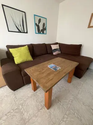 a living room with a brown couch and a wooden table at Bonne Chance Apartment Sozopol in Sozopol